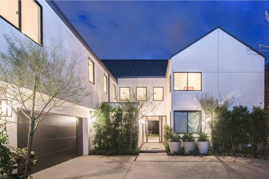 Ejemplo de fachada de casa blanca minimalista grande de dos plantas con revestimiento de estuco y tejado a dos aguas