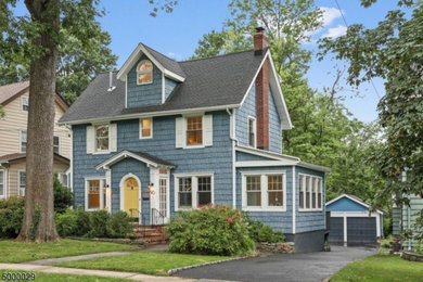 Elegant blue three-story vinyl and shingle exterior home photo in New York with a shingle roof and a gray roof