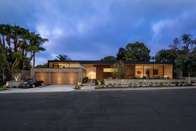 Foto på ett stort funkis brunt hus, med allt i ett plan, blandad fasad och platt tak
