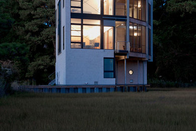 Diseño de fachada beige moderna de tamaño medio de tres plantas con revestimiento de madera y tejado plano