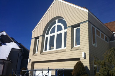 Imagen de fachada de casa beige clásica grande de dos plantas con revestimiento de madera y tejado a dos aguas