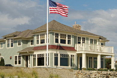 Cette image montre une grande façade de maison verte marine en bois à un étage avec un toit à quatre pans.