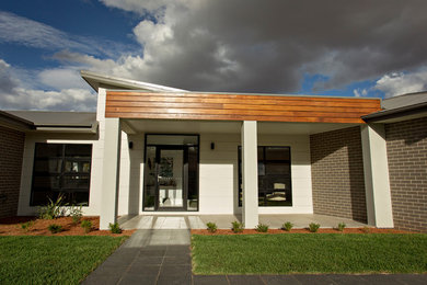 Modelo de fachada gris contemporánea grande a niveles con revestimiento de ladrillo y tejado a dos aguas