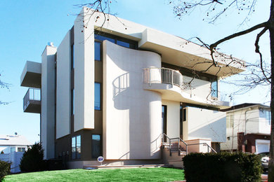 This is an example of a large and beige modern two floor render house exterior in New York with a flat roof.
