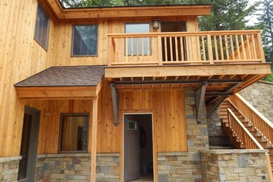 Cette image montre une grande façade de maison marron chalet en bois à un étage avec un toit à deux pans et un toit en shingle.
