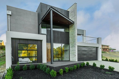 Ejemplo de fachada de casa gris grande de dos plantas con revestimiento de ladrillo, tejado plano y tejado de metal