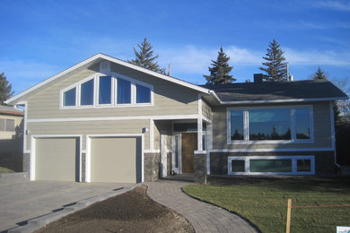Imagen de fachada de casa gris tradicional de tamaño medio a niveles con revestimiento de aglomerado de cemento, tejado a dos aguas y tejado de teja de madera