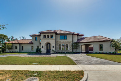 Example of a large tuscan beige two-story stucco house exterior design in Dallas with a tile roof