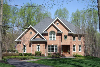 Large contemporary brown two-story brick house exterior idea in DC Metro with a hip roof and a mixed material roof