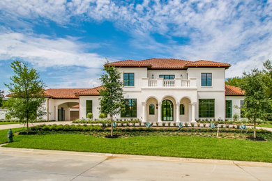 Example of a tuscan beige two-story house exterior design in Dallas with a hip roof, a tile roof and a red roof