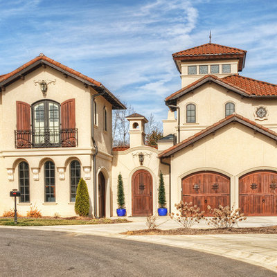 Example of a large tuscan beige three-story stucco gable roof design in Charlotte