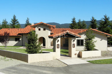 This is an example of a medium sized and beige bungalow render house exterior in Los Angeles with a pitched roof.