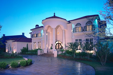 Imagen de fachada de casa blanca mediterránea grande de dos plantas con revestimiento de estuco, tejado a dos aguas y tejado de teja de barro