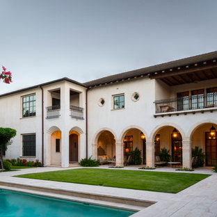 Example of a huge tuscan white two-story stucco house exterior design in Houston with a hip roof and a tile roof