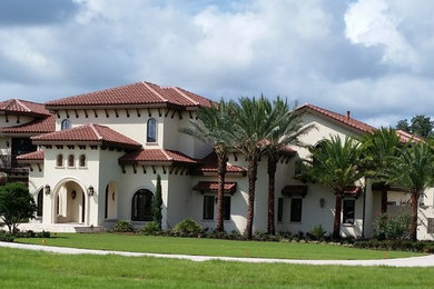 Design ideas for an expansive and white mediterranean two floor clay house exterior in Orlando with a hip roof.