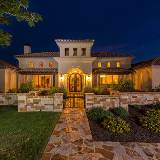 Foto della facciata di una casa grande beige mediterranea a due piani con tetto a padiglione e rivestimento in stucco