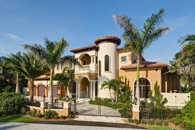 Tuscan beige two-story adobe exterior home photo in Miami