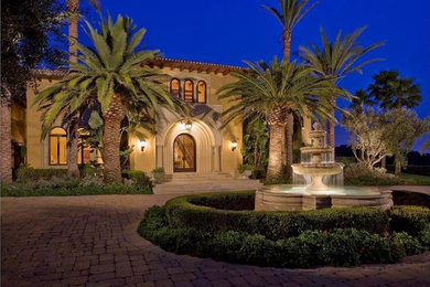 Example of a huge tuscan beige two-story stucco house exterior design in Other with a hip roof and a tile roof