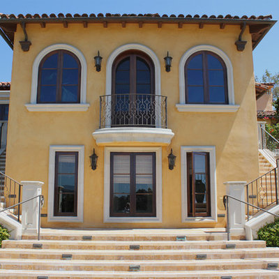 Inspiration for a large mediterranean yellow two-story house exterior remodel in Santa Barbara with a hip roof and a tile roof