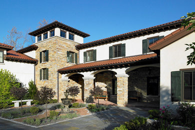 Inspiration for a large mediterranean yellow two-story stone exterior home remodel in Milwaukee