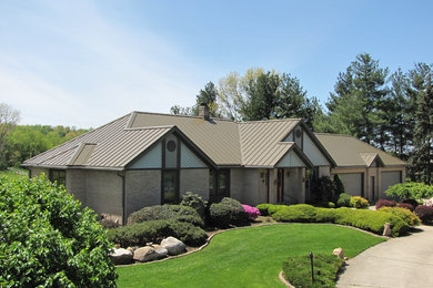 Cette photo montre une façade de maison marron tendance en brique de plain-pied avec un toit à quatre pans.