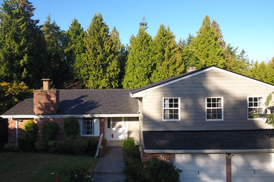 Imagen de fachada de casa gris tradicional de dos plantas con revestimiento de vinilo, tejado a dos aguas y tejado de teja de madera