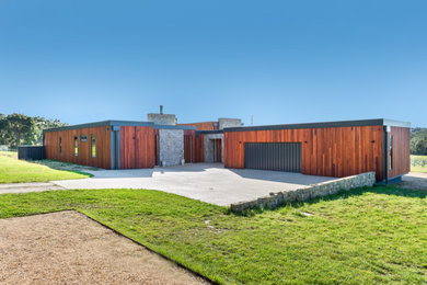 Foto della villa ampia marrone contemporanea a un piano con rivestimento in legno, tetto piano e copertura in metallo o lamiera