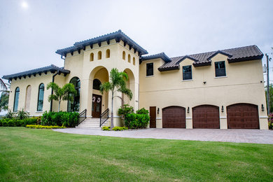 Example of a large tuscan yellow two-story stucco house exterior design in Orlando with a tile roof