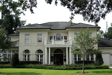 Inspiration for a large mediterranean white two-story brick exterior home remodel in New Orleans with a hip roof