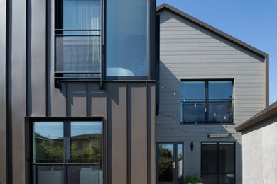 Imagen de fachada de casa actual de tamaño medio de dos plantas con revestimiento de metal, tejado de un solo tendido y tejado de metal