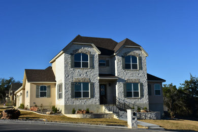Large french country yellow two-story stone exterior home idea in Austin with a shingle roof