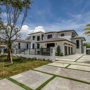 Large modern white two-story stucco exterior home idea in Miami with a shingle roof