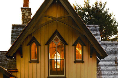 Стильный дизайн: желтый, большой, трехэтажный, деревянный частный загородный дом в стиле ретро с двускатной крышей и крышей из гибкой черепицы - последний тренд