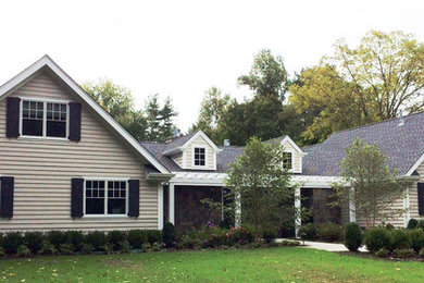 Modelo de fachada beige vintage de tamaño medio de dos plantas con tejado a dos aguas y revestimiento de aglomerado de cemento