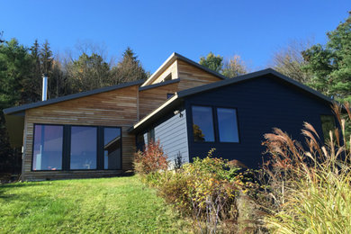 Modelo de fachada de casa azul vintage de tamaño medio de dos plantas con revestimiento de madera, tejado de un solo tendido y tejado de metal