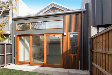 Cette photo montre une façade de maison grise tendance en bois à un étage avec un toit en métal.