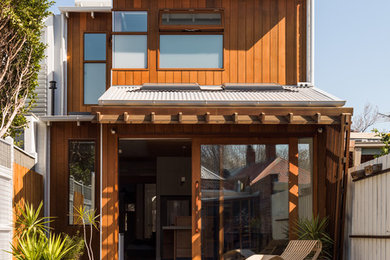 Idée de décoration pour une façade de maison container marron design en bois à un étage avec un toit en appentis et un toit en métal.