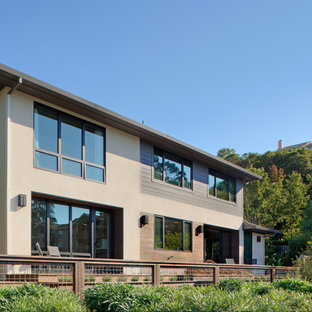 Large mid-century modern beige two-story stucco house exterior photo in San Francisco with a hip roof and a shingle roof
