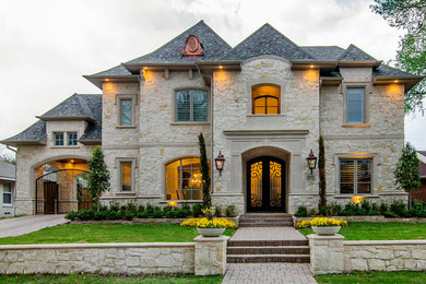 Пример оригинального дизайна: двухэтажный, бежевый дом в классическом стиле с облицовкой из камня и вальмовой крышей