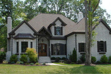 Example of a large classic gray two-story brick exterior home design in Raleigh with a clipped gable roof