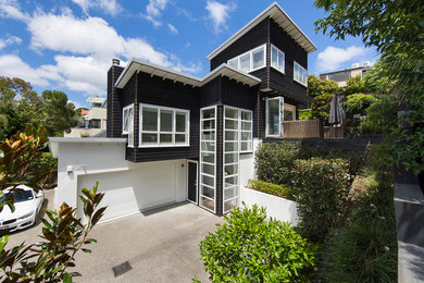 Großes, Dreistöckiges Rustikales Haus mit schwarzer Fassadenfarbe und Blechdach in Auckland