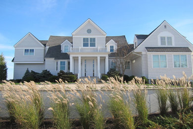 Cette photo montre une façade de maison beige chic en bois de taille moyenne et de plain-pied avec un toit à deux pans.