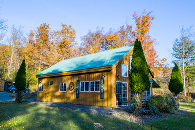 Ejemplo de fachada de casa marrón rústica de tamaño medio de dos plantas con revestimiento de madera, tejado a dos aguas y tejado de metal