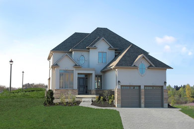 Example of a classic beige house exterior design in Toronto with a shingle roof