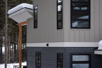 Example of a minimalist gray three-story concrete fiberboard flat roof design in Calgary