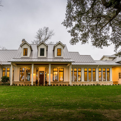 Inspiration for a large country white two-story concrete fiberboard house exterior remodel in Houston with a hip roof and a metal roof