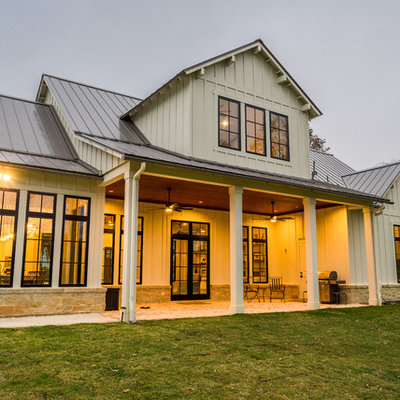Large cottage beige two-story concrete fiberboard exterior home photo in Houston with a metal roof