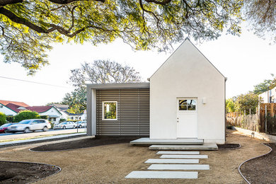 Ejemplo de fachada de casa blanca minimalista grande a niveles con revestimiento de estuco y tejado a cuatro aguas