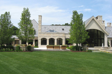 Esempio della villa grande beige classica a due piani con rivestimenti misti, tetto a padiglione e copertura a scandole