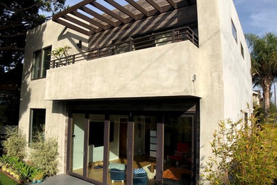 Ejemplo de fachada de casa gris minimalista grande de dos plantas con revestimiento de estuco, tejado plano y tejado de varios materiales